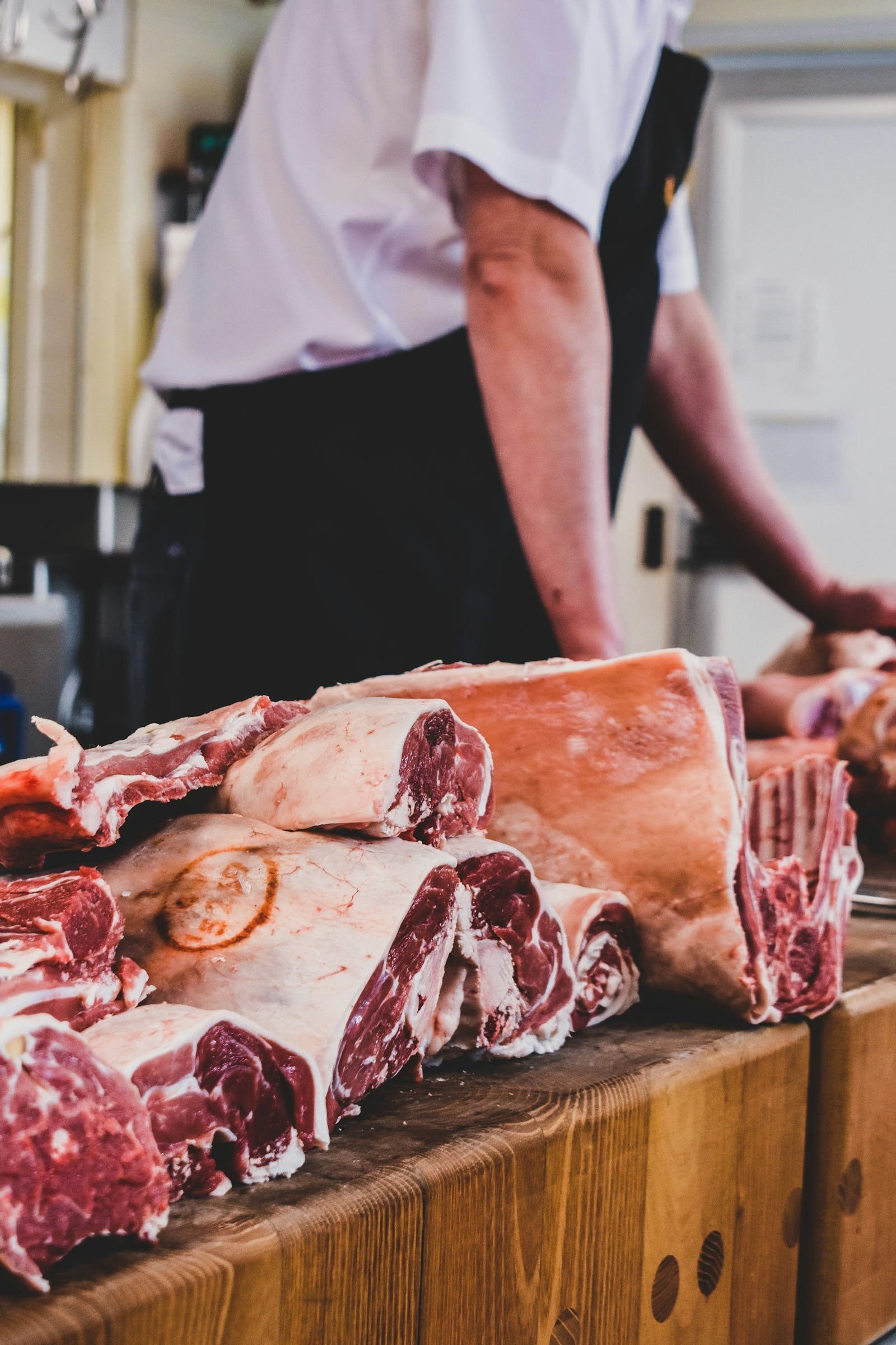 A butcher preparing cuts of meat in a preparation room